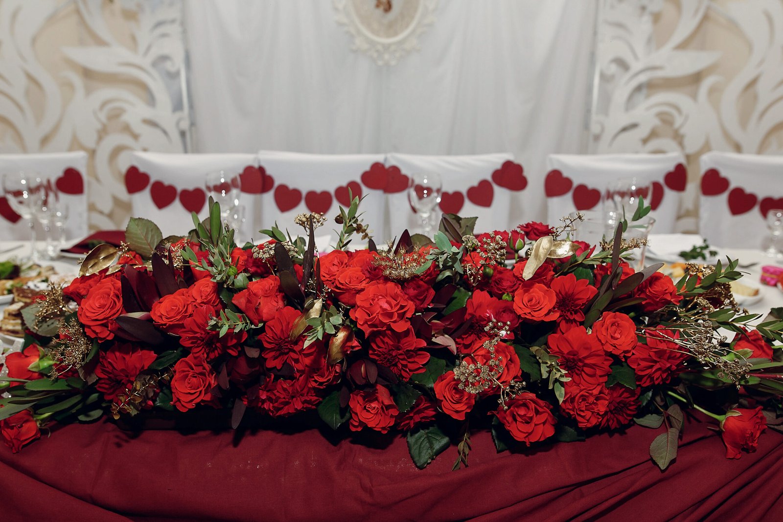 stylish centerpiece table for bride and groom with red roses, luxury decorated place for wedding ceremony and reception