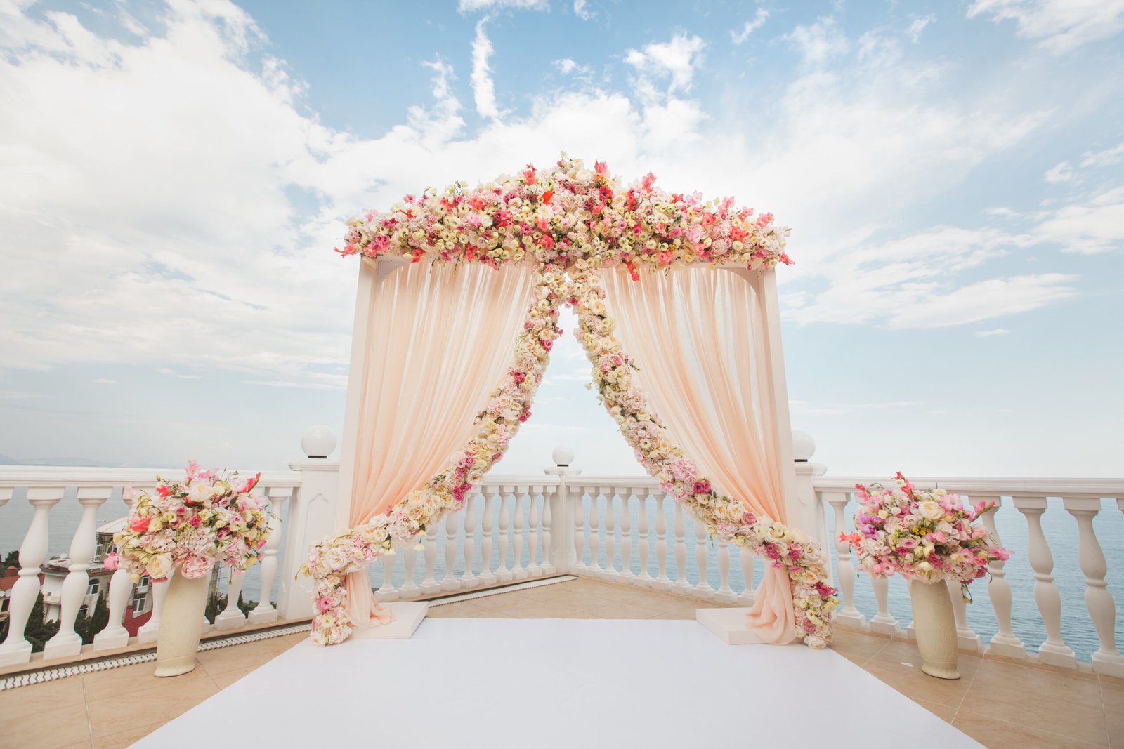 Wedding arch peach color with flowers on the background of the sea. Vases with fresh flowers.